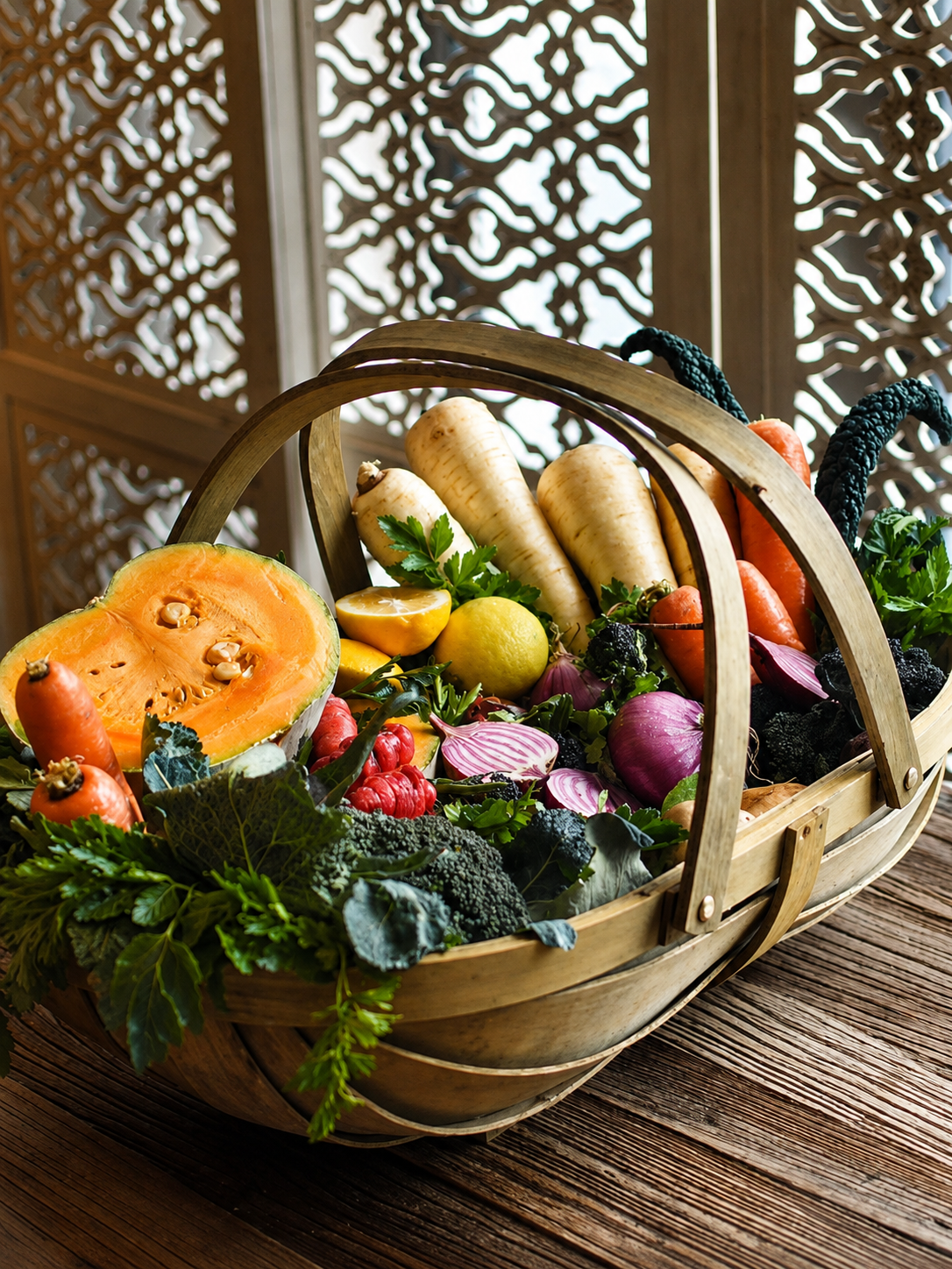 A basket filled with fresh vegetables, herbs and citrus