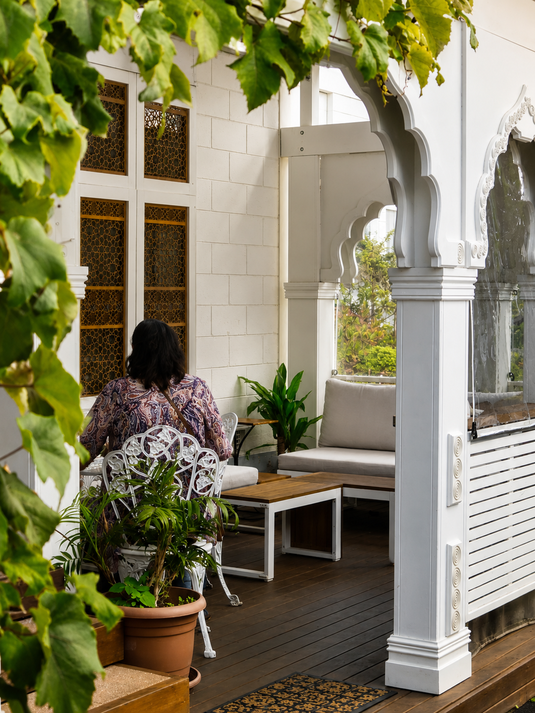 A leafy outdoor dining terrace with arched details