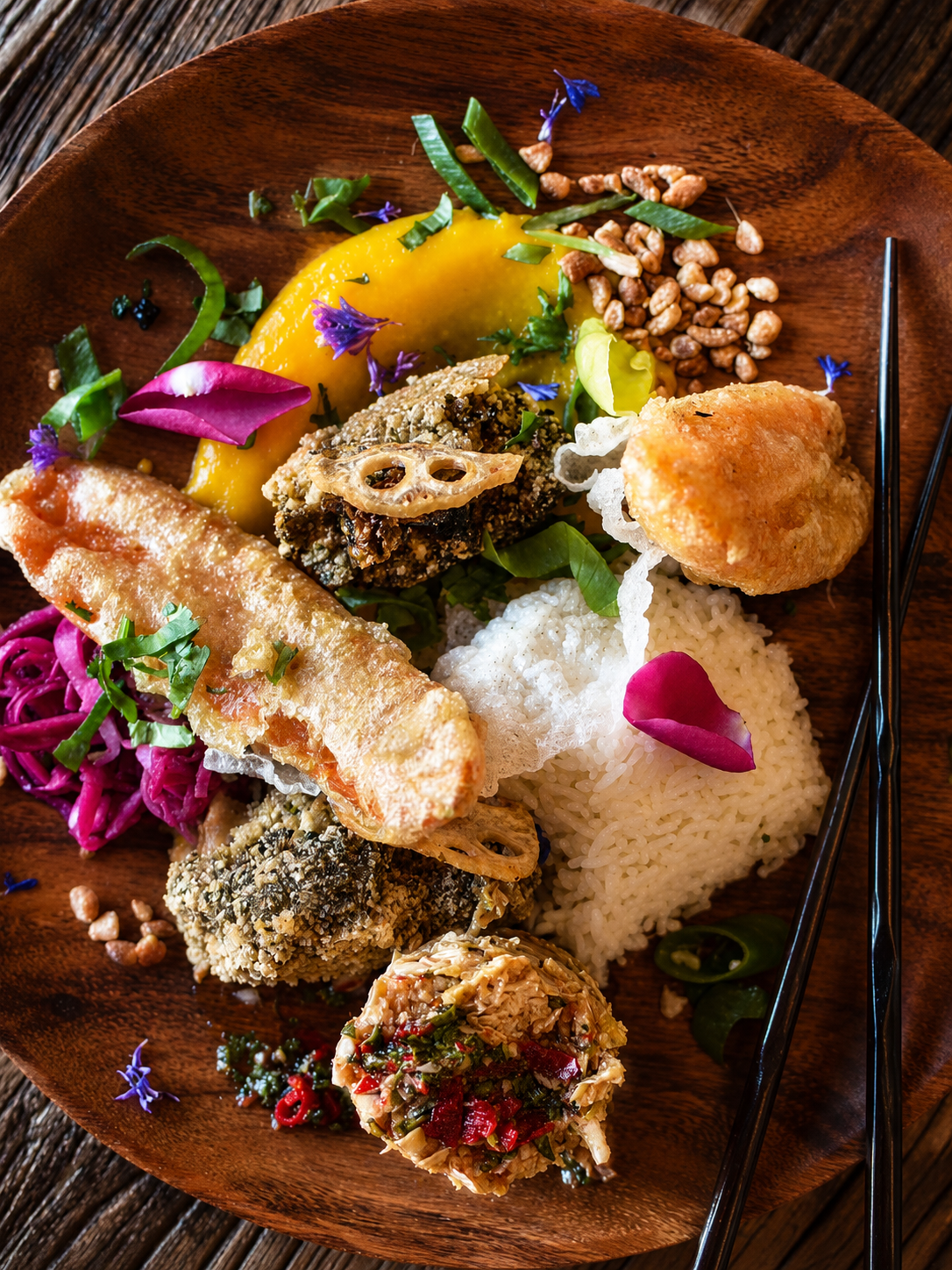 An artfully plated vegetarian dinner with rice, vegetables and edible flowers